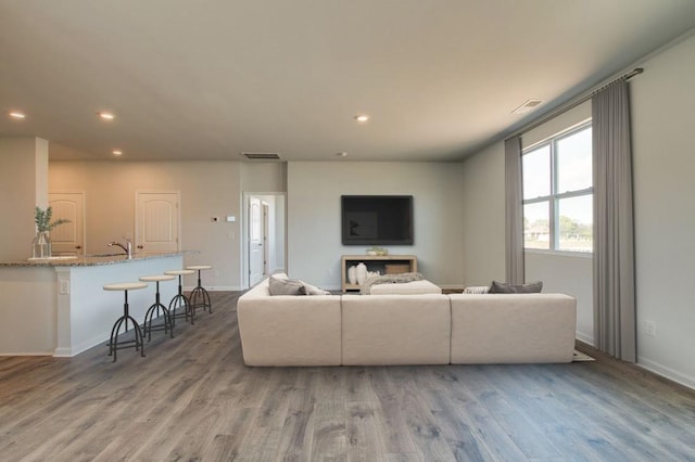 living room with recessed lighting, visible vents, and wood finished floors