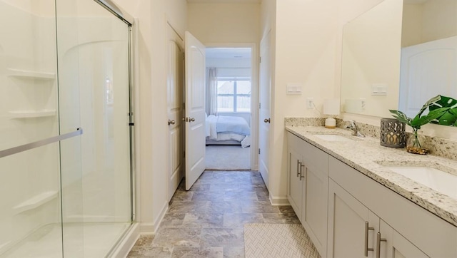 ensuite bathroom featuring double vanity, a stall shower, a sink, and baseboards