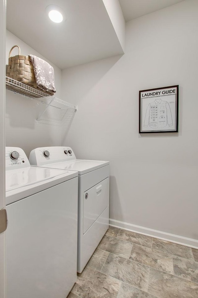 washroom with laundry area, stone finish floor, washer and clothes dryer, and baseboards