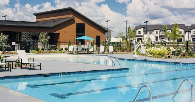 pool with a residential view, fence, and a patio