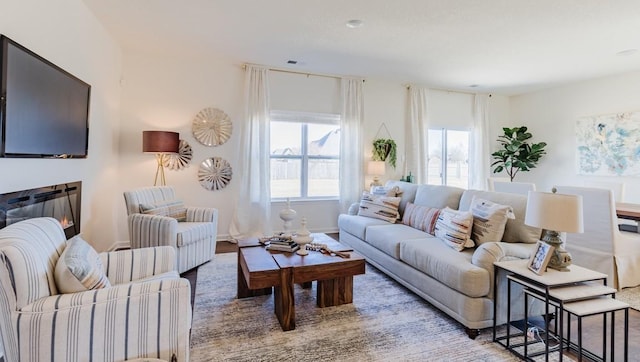 living area featuring a glass covered fireplace and baseboards