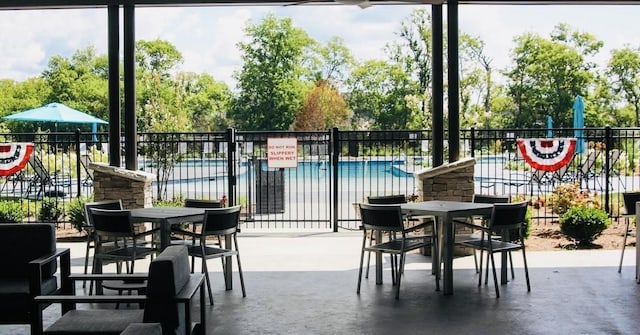 view of patio featuring outdoor dining area, fence, and a community pool