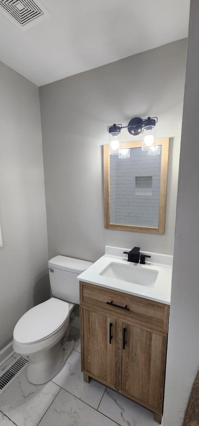 half bathroom featuring marble finish floor, visible vents, vanity, and toilet