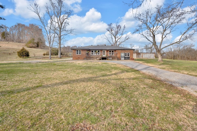 view of front of house featuring driveway, a deck, a front lawn, and brick siding