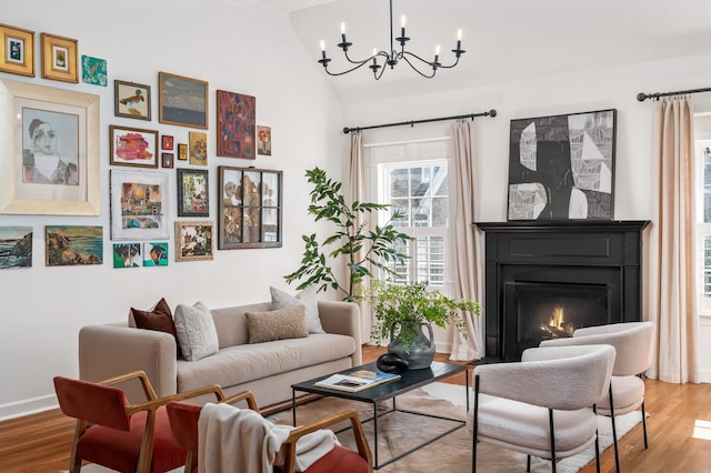 living room featuring vaulted ceiling, wood finished floors, a glass covered fireplace, and baseboards