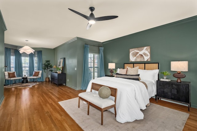 bedroom featuring multiple windows, crown molding, baseboards, and wood finished floors