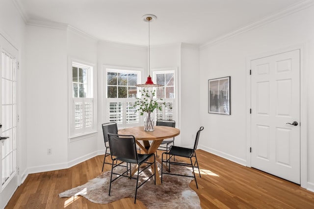 dining space with baseboards, ornamental molding, and wood finished floors