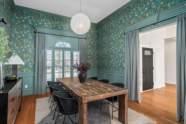 dining room with wallpapered walls, crown molding, and wainscoting