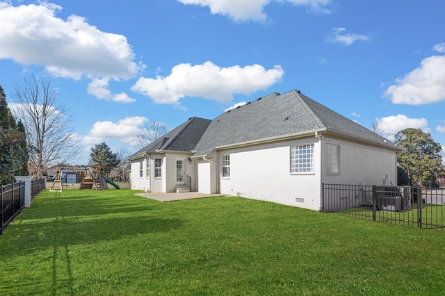 back of house featuring brick siding, a playground, a lawn, crawl space, and a fenced backyard