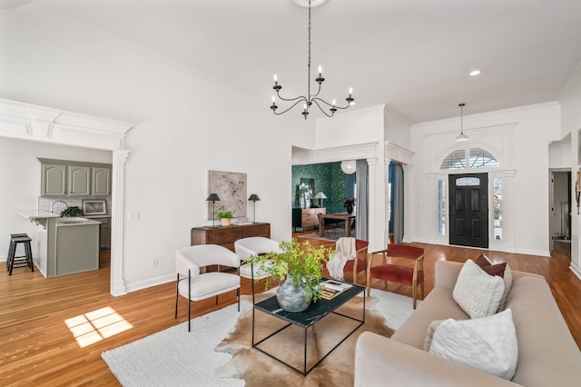 living room with ornamental molding, baseboards, a notable chandelier, and light wood finished floors