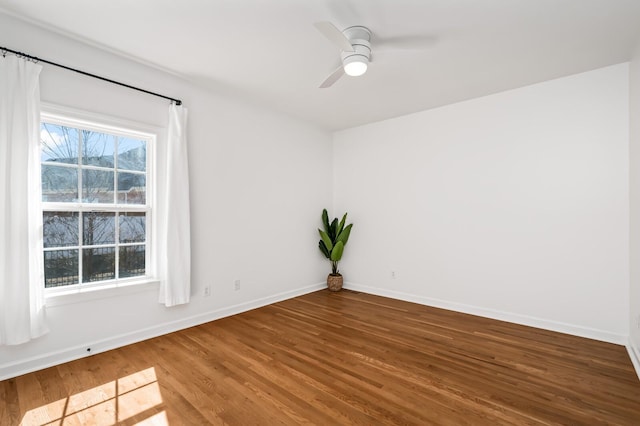 empty room with ceiling fan, baseboards, and wood finished floors