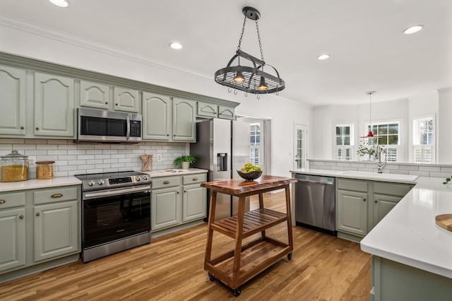 kitchen featuring stainless steel appliances, decorative light fixtures, a sink, and ornamental molding