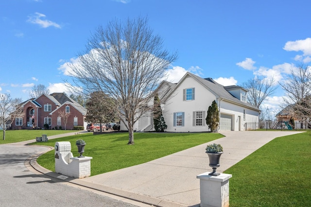 view of front facade with a front yard, concrete driveway, fence, and stucco siding