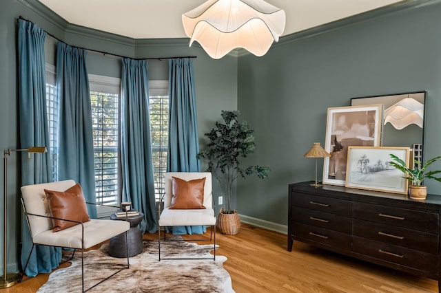 living area with baseboards, crown molding, and light wood finished floors