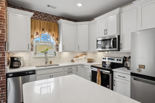 kitchen with appliances with stainless steel finishes, light countertops, visible vents, and a sink