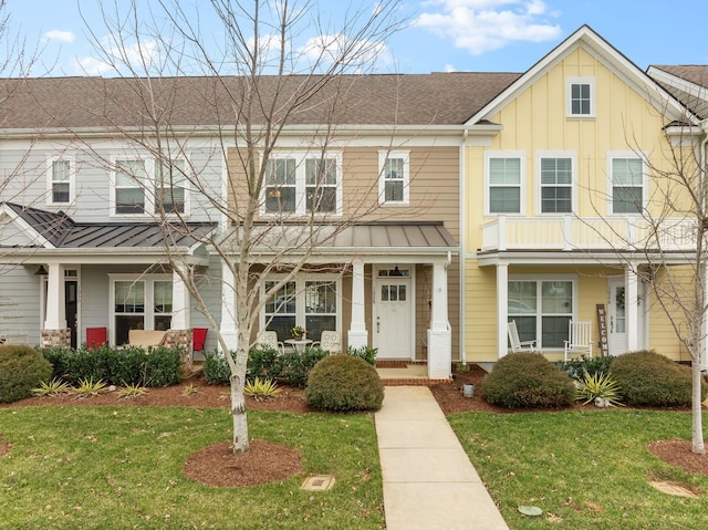 townhome / multi-family property featuring board and batten siding, a front yard, covered porch, and a standing seam roof