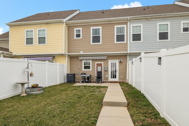 rear view of house featuring cooling unit, a fenced backyard, a lawn, and a patio