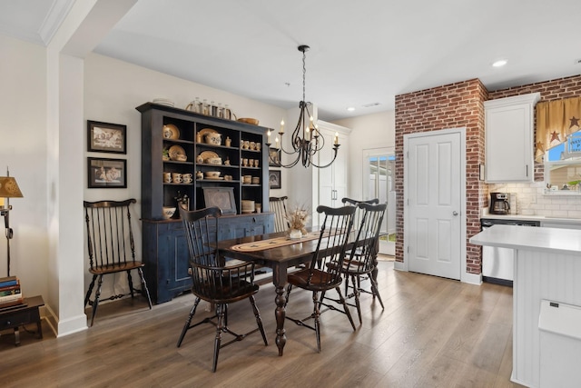 dining space featuring recessed lighting, light wood-style floors, brick wall, a chandelier, and baseboards