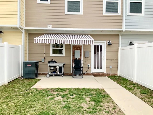 rear view of property featuring central air condition unit, a patio area, fence, and a lawn