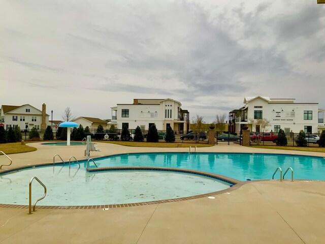 community pool with a patio area and fence