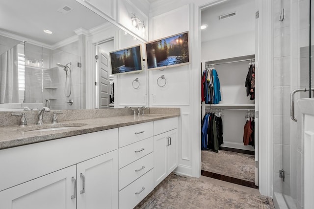 bathroom featuring a sink, a spacious closet, a shower stall, and visible vents