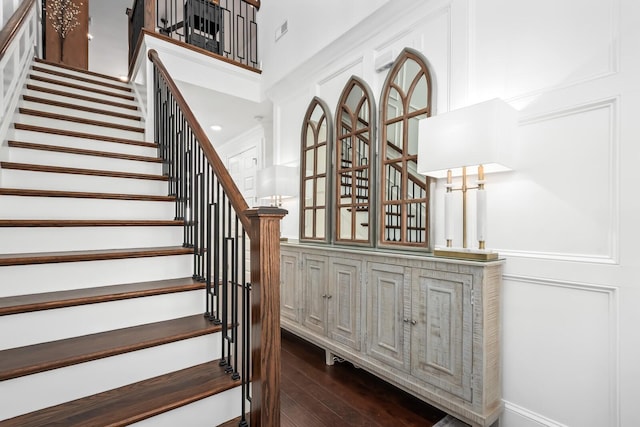 stairs featuring visible vents, a towering ceiling, and wood finished floors