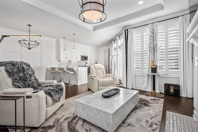 living room featuring ornamental molding, a raised ceiling, and wood finished floors