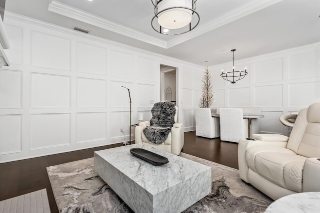 living room with visible vents, a decorative wall, a raised ceiling, and ornamental molding