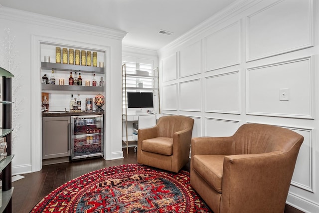 sitting room featuring beverage cooler, dark wood-type flooring, visible vents, ornamental molding, and a dry bar