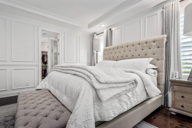 bedroom featuring crown molding, dark wood-style flooring, and a decorative wall