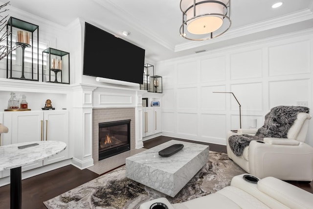 living room with a decorative wall, a fireplace with flush hearth, visible vents, ornamental molding, and dark wood finished floors