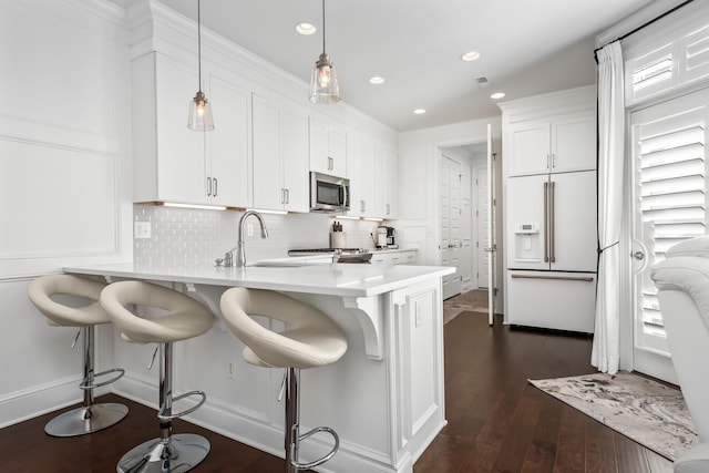 kitchen featuring white cabinets, stainless steel microwave, a kitchen breakfast bar, high end white fridge, and light countertops