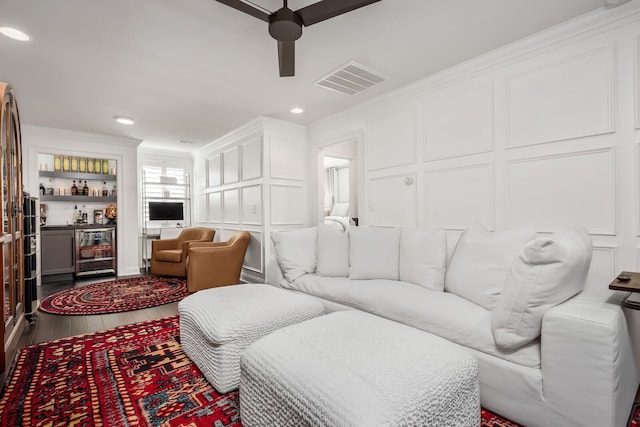 living area featuring a dry bar, beverage cooler, visible vents, ornamental molding, and a decorative wall