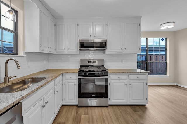 kitchen with stainless steel appliances, light wood-type flooring, a sink, and white cabinets