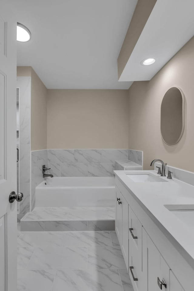 full bathroom with marble finish floor, double vanity, a sink, and a bath