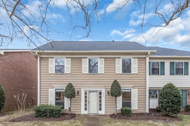 colonial house featuring a shingled roof