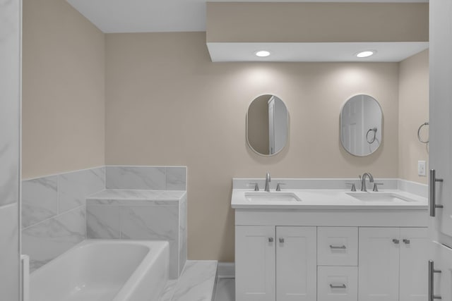 full bathroom featuring double vanity, marble finish floor, a sink, and a bath