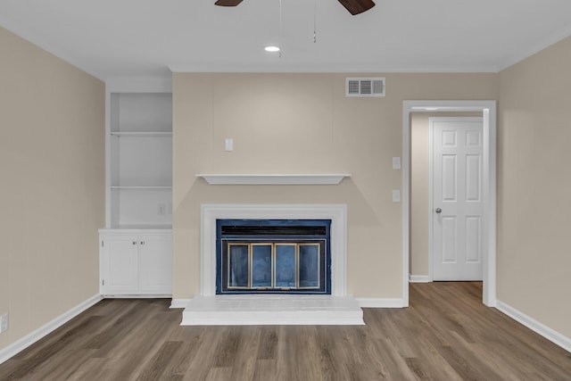 unfurnished living room featuring a glass covered fireplace, visible vents, baseboards, and wood finished floors