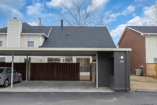 view of front of property with cooling unit, fence, covered parking, roof with shingles, and board and batten siding