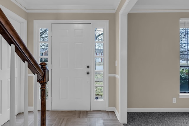 foyer with a healthy amount of sunlight, crown molding, and baseboards