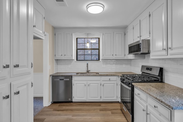 kitchen with light wood finished floors, visible vents, white cabinets, appliances with stainless steel finishes, and a sink