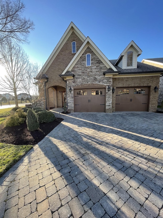 view of front of property featuring brick siding, an attached garage, and decorative driveway