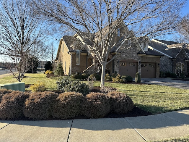 view of front facade with a garage, concrete driveway, stone siding, a front yard, and brick siding