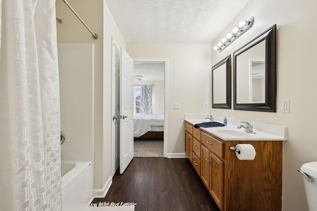 bathroom featuring a textured ceiling, double vanity, wood finished floors, and a sink