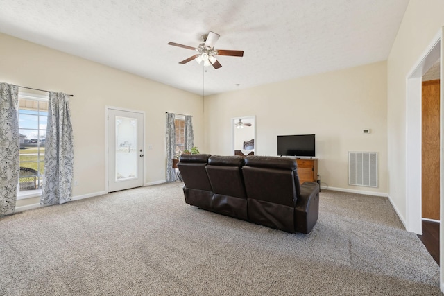 carpeted living area with visible vents, ceiling fan, a textured ceiling, and baseboards