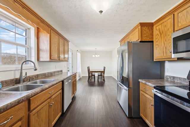 kitchen with brown cabinets, appliances with stainless steel finishes, dark wood-type flooring, and a sink