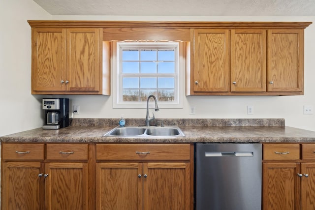 kitchen featuring brown cabinetry, dark countertops, a sink, and stainless steel dishwasher