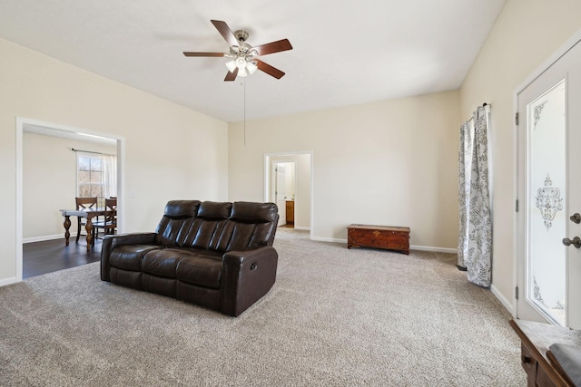 living room featuring carpet, baseboards, and ceiling fan