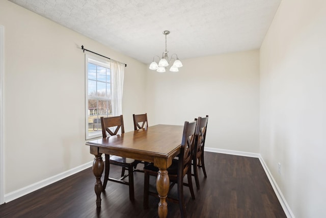 dining space with a textured ceiling, dark wood-type flooring, an inviting chandelier, and baseboards