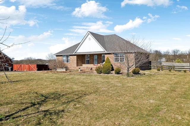 view of front of house with an outbuilding, a front lawn, fence, and brick siding